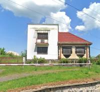 A family house in Nová Bašta with a white facade, a red roof, and a green lawn.