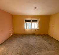 A spacious room with a window and light yellow and peach walls in a family house.