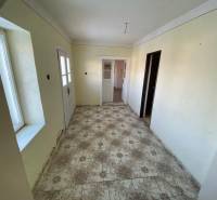 Hallway in a family house with a tiled floor and doors.