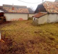 A garden at a family house in Nová Bašta, with old buildings and a lawn in the background.