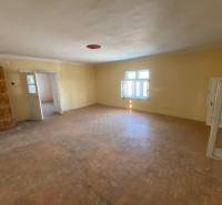 A spacious room with a wood-patterned floor and open white windows.