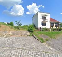 A family house in Nová Bašta surrounded by a green lawn and a paved walkway.