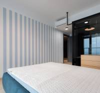 Bedroom in a 2-room apartment with a patterned wall, bed, and air conditioning.