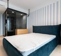 Bedroom in a 2-room apartment with a blue bed and a striped wall, floor with wood decor.