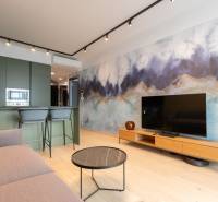 Living room in a two-room apartment, with a wooden decor floor and an artistic wall.