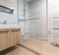 Bathroom with a sink on a wooden cabinet, a shower corner, and a floor with a wooden decor.