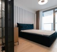 Bedroom with a large bed, wooden decor flooring, and access to a balcony in a 2-room apartment.