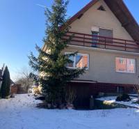 A family house in Rudník, with a gabled roof, trees, and a snowy yard.