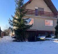 Family house in Rudník on Rudník Street with wooden cladding and a snowy garden.