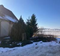 The snowy surroundings of a family house in Rudník, shrubs and trees on Rudník Street.