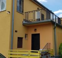 Yellow facade of a family house in Stretavka with a balcony and wrought iron window grilles.