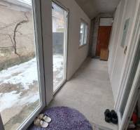 A corridor with large windows and doors, a floor with ceramic tiles in a family house.