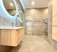 Bathroom with a round mirror, shower corner, and wooden decor in a 3-room apartment.