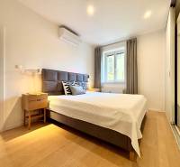 Bedroom in a 3-room apartment with a bed, nightstand, and wooden decor flooring.