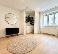 A room with a wooden decor floor, a carpet, a mirror, and a curtain in a 3-room apartment.
