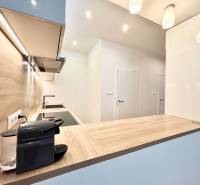 A kitchen in a 3-room apartment with a wooden decor floor and built-in lighting.
