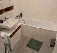 Bathroom in a 2-room apartment with a bathtub, sink, and washing machine.