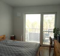 Bedroom in a 2-room apartment with a bed and a balcony, floor with wooden decor.