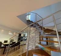A staircase with a metal railing, a dining table, and a floor with a wooden decor in a 3-room apartment.