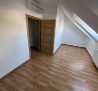 Attic with air conditioning and wooden decor flooring in a 3-room apartment.