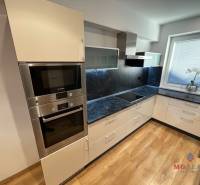 A kitchen in a 3-room apartment with white cabinets and a wood-patterned floor.