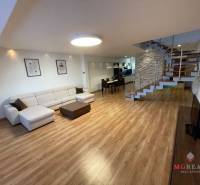 Living room in a 3-room apartment with a wooden decor floor and a designer staircase.