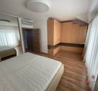 Bedroom with a bed, built-in wardrobe, and wooden decor flooring in a 3-room apartment.