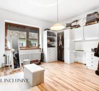 A wardrobe in a family house with white cabinets and a wooden decor floor.