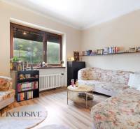 Living room in a family house with floral sofas and a wooden-patterned floor.
