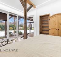 A bedroom in a family house with a view of the snowy garden, wooden decor, and massive beams.