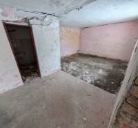 An abandoned room in a family house with bare walls and a broken floor.