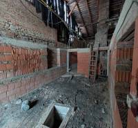 Unfinished interior in a family house with an exposed ceiling and brick walls.