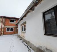 Snow-covered yard of a family house on Remeselnícka Street in Ľubica, brick and plastered walls.