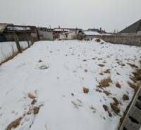 A snow-covered plot in Ľubica on Remeselnícka Street, surrounded by fences and family house buildings.