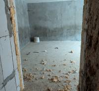 A room in a family house with a concrete floor, visible construction foam, and rough walls.