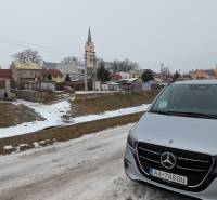 A view of the snow-covered Remeselnícka Street in Ľubica with family houses and a car.