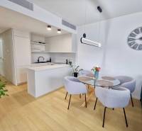 Dining table with chairs in a 3-room apartment, white walls, wooden decor flooring.
