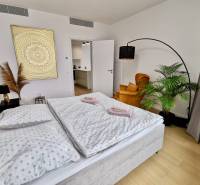 Bedroom with a double bed, plant, chair, and painting, floor with wood decor.