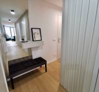 Hallway of a 3-room apartment with a decorative table and wooden-patterned flooring.
