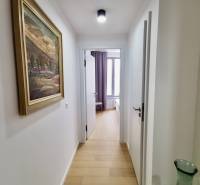 A hallway in a 3-room apartment with a wooden decor floor and a painting on the wall.