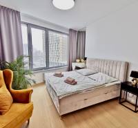 Bright bedroom in a 3-room apartment with large windows, a bed, and a chair.