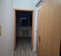 A narrow hallway in an office with a wooden decor floor and air conditioning.