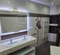 A bathroom in a family house with two sinks, a large mirror, and a radiator.