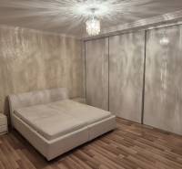 A bedroom in a family house with a large wardrobe, a bed, and a wooden decor floor.