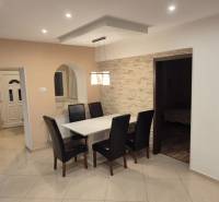 Dining room with leather chairs, a white table, and brick cladding in a family house.