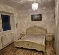 Bedroom in a family house with wooden floor decor, a bed, and a painting on the wall.