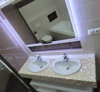 A bathroom in a family house with a double sink and an illuminated mirror.