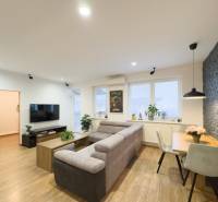 Living room with wood-patterned flooring in a 3-room apartment, with a sofa and a dining table.