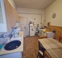 A kitchen in a family house with a wooden decor floor, a table, and kitchen cabinets.