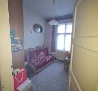 A room in a family house with a sofa, carpet, and curtains on the windows.